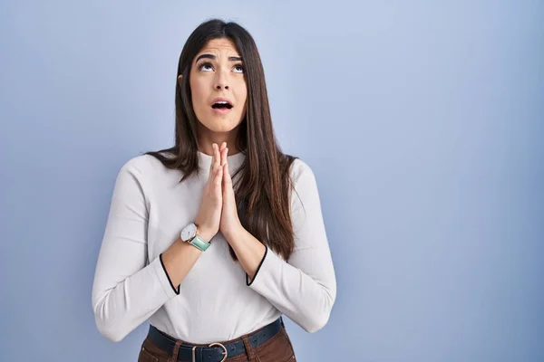 Genç Esmer Kadın Mavi Arka Planda Duruyor Elleriyle Yalvarıyor Dua — Stok fotoğraf