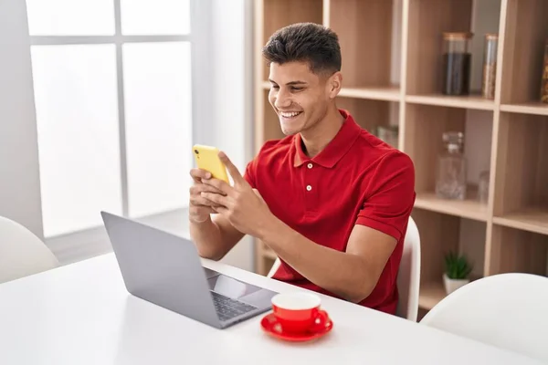 Young Hispanic Man Using Laptop Smartphone Sitting Table Home — Stockfoto