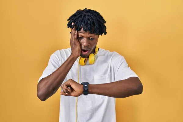 Young African Man Dreadlocks Standing Yellow Background Looking Watch Time — Stok fotoğraf