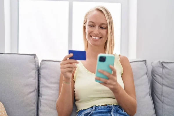Mladá Blondýna Žena Pomocí Smartphone Kreditní Karty Sedí Pohovce Doma — Stock fotografie