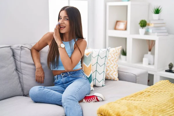 Genç esmer kadın kanepede oturuyor, eli ağızda gizli dedikodular anlatıyor, kötü niyetli konuşmalar fısıldıyor. 