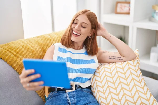 Young Redhead Woman Watching Video Touchpad Sitting Sofa Home — Stockfoto