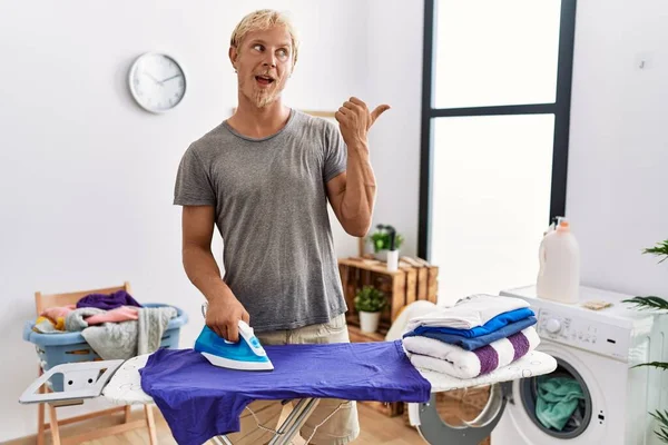 Çamaşır Odasında Giysilerini Ütüleyen Genç Sarışın Adam Baş Parmağını Yukarı — Stok fotoğraf