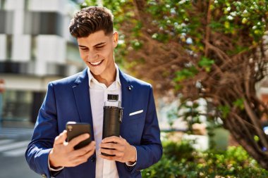 Genç adam parkta akıllı telefon kullanıyor.