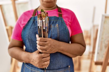 Kıdemli Afro-Amerikan kadın sanat stüdyosunda boya fırçası tutuyor.