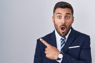 Yakışıklı, takım elbiseli ve kravatlı bir adam parmaklarıyla yan tarafı göstererek şaşırdı, ağzı açık hayret içinde kaldı.. 