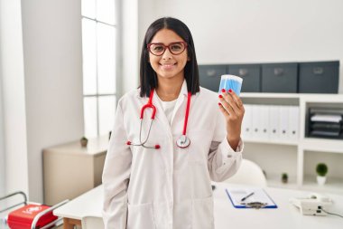 Pamuk tomurcukları tutan genç İspanyol doktor olumlu ve mutlu görünüyor ve kendine güvenen bir gülümsemeyle dişlerini gösteriyor. 