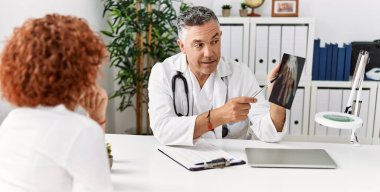 Doktor üniforması giyen orta yaşlı bir adam ve kadın klinikte tıbbi danışmanlık yapıyorlar.