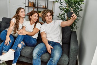 Anne ve çift kendilerine güvenerek evde akıllı telefondan selfie çekiyorlar.