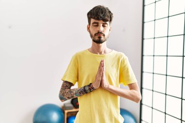 Spor merkezinde yoga eğitimi alırken gülümseyen İspanyol genç adam..
