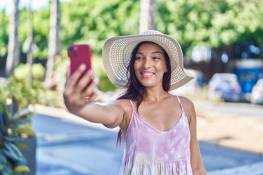 Genç ve güzel İspanyol kadın turist gülümsüyor. Parktaki akıllı telefondan özçekim yapıyor.