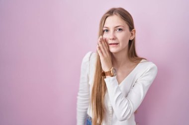 Pembe arka planda duran beyaz bir kadın. Ağız üstünde el ele. Gizli dedikodular, kötü niyetli konuşmalar. 