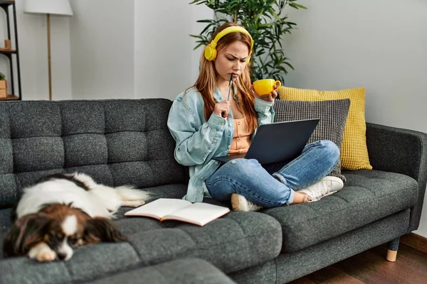 若いですCaucasian女性座っています上のソファとともに犬勉強ホーム — ストック写真