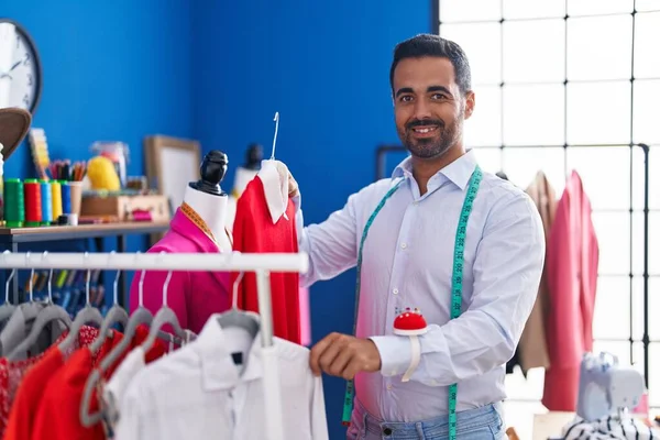 Young Hispanic Man Tailor Smiling Confident Holding Clothes Rack Sewing — Stockfoto