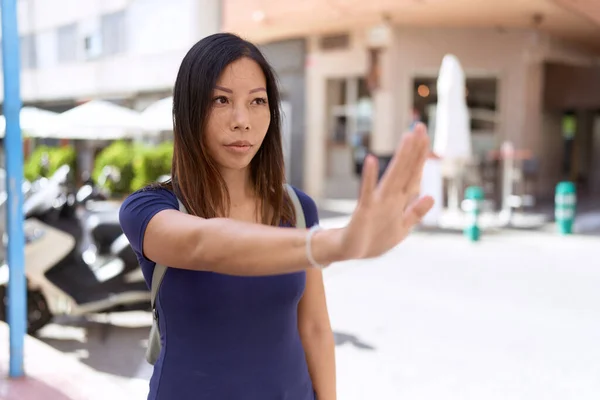 Young asian woman doing stop gesture with hand at coffee shop terrace