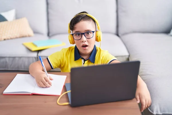 Young Hispanic Kid Doing Homework Laptop Home Scared Amazed Open — Stok fotoğraf