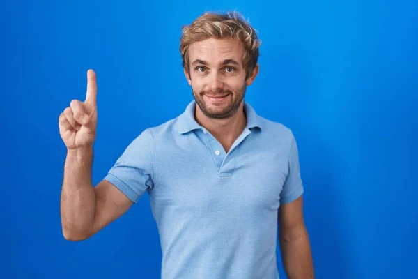 Caucasian Man Standing Blue Background Showing Pointing Finger Number One — Zdjęcie stockowe