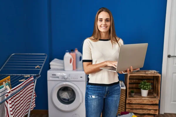 Young Blonde Woman Smiling Confident Using Laptop Laundry Room — Stockfoto