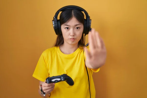 中国的年轻女子正在玩电子游戏 手握着控制器 停止了用手掌唱歌 用消极而严肃的手势警告人 — 图库照片
