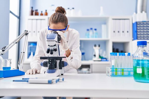 Young woman scientist using microscope working at laboratory