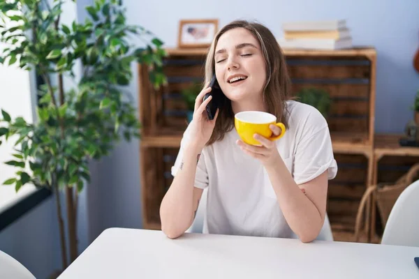 Νεαρή Γυναίκα Πίνει Καφέ Και Μιλάει Στο Smartphone Στο Σπίτι — Φωτογραφία Αρχείου