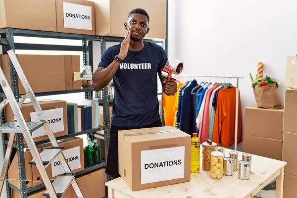 Young African American Volunteer Man Packing Donations Box Charity Touching — Zdjęcie stockowe
