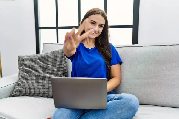 Genç Esmer Kadın Evinde Dizüstü Bilgisayar Kullanıyor Gülümsüyor Parmaklarını Zafer — Stok fotoğraf