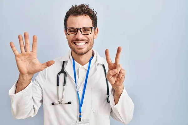 身穿医生制服 头戴听诊器的年轻人 带着自信和快乐的笑容 用七号手指显示和指尖 — 图库照片