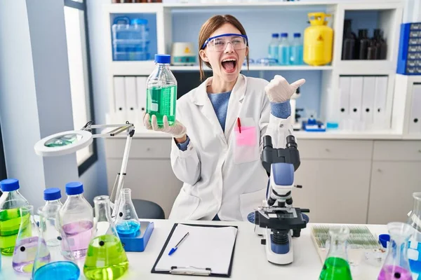 Young Brunette Woman Working Scientist Laboratory Pointing Thumb Side Smiling — ストック写真