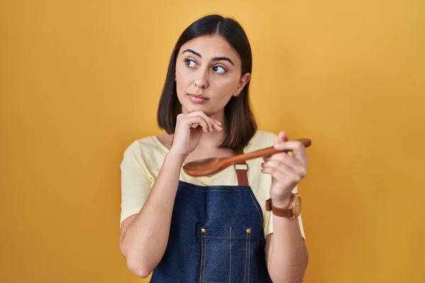 Hispanic Girl Eating Healthy Wooden Spoon Hand Chin Thinking Question — Zdjęcie stockowe