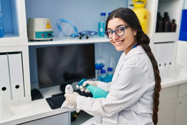 研究室でサニタイザージェルを使って科学者の制服を着た若いヒスパニック系の女性 — ストック写真
