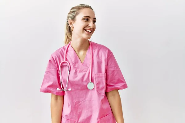 年轻的金发女子身穿粉色护士制服 背景孤寂 面带微笑 神态自然 充满自信地大笑 — 图库照片