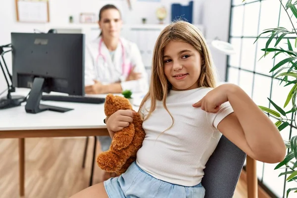 Blondi Pieni Tyttö Pediatrian Klinikalla Jossa Naislääkäri Osoittaa Sormella Yhtä — kuvapankkivalokuva