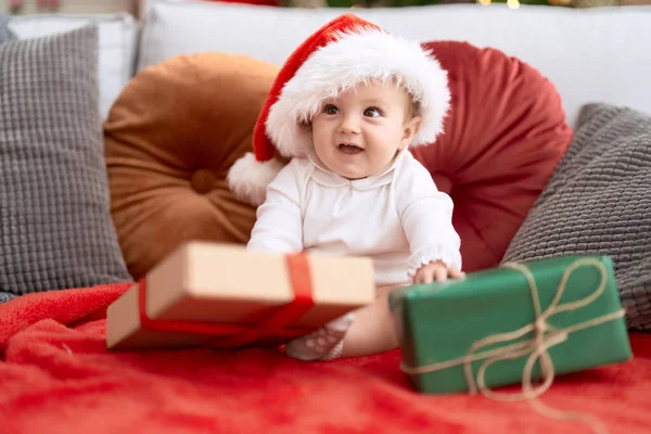 可爱的小孩戴着圣诞礼帽坐在沙发上 家里也有礼物 — 图库照片