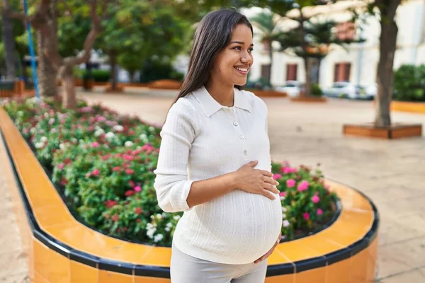 Młoda Latynoska Kobieta Ciąży Uśmiecha Się Pewnie Dotykając Brzucha Parku — Zdjęcie stockowe