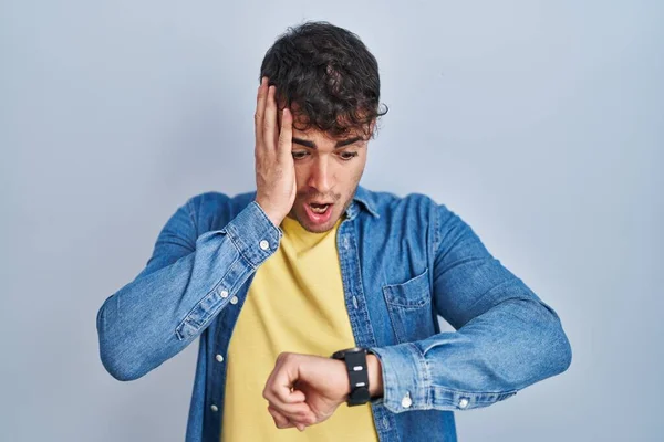 Genç Spanyol Adam Mavi Arka Planda Dikiliyor Saate Bakıyor Endişeli — Stok fotoğraf