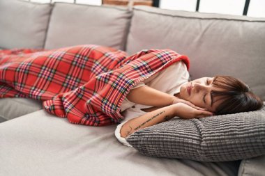 Young beautiful hispanic woman lying on sofa sleeping at home