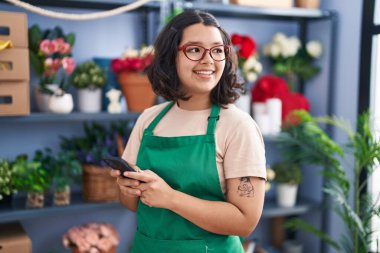 Young woman florist smiling confident using smartphone at florist