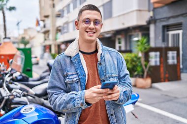 Sokakta akıllı telefon kullanan, kendine güvenen genç bir İspanyol.