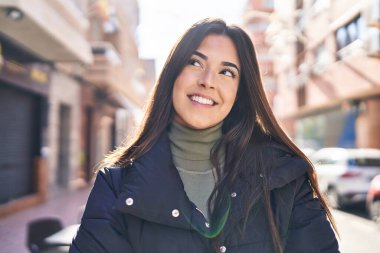 Young beautiful hispanic woman smiling confident looking to the side at street