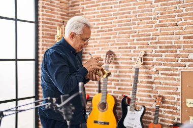 Kıdemli müzisyen müzik stüdyosunda trompet çalıyor.