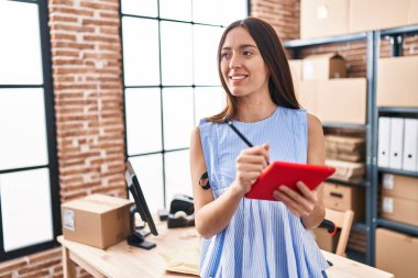 Genç, güzel, İspanyol bir kadın. İş kadını. Ofiste dokunmatik ped kullanıyor.