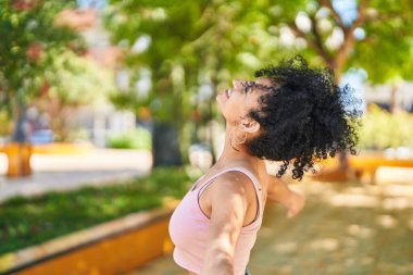 Genç İspanyol kadın gülümsüyor. Parkta nefes alıyor.