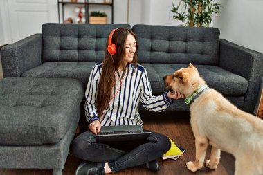 Genç İspanyol kadın dizüstü bilgisayar kullanıyor evde köpekle oturuyor.