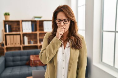 Hispanic woman working at consultation office feeling unwell and coughing as symptom for cold or bronchitis. health care concept. 