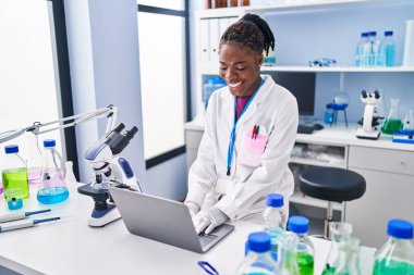Laboratuvarda dizüstü bilgisayar kullanan Afrikalı Amerikalı kadın.
