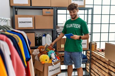Genç Arap adam gönüllü üniforması giyiyor. Yardım merkezinde dokunmatik ped kullanıyor.