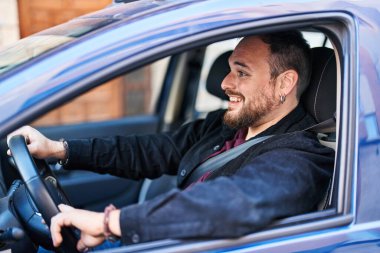 Young hispanic man smiling confident driving car at street