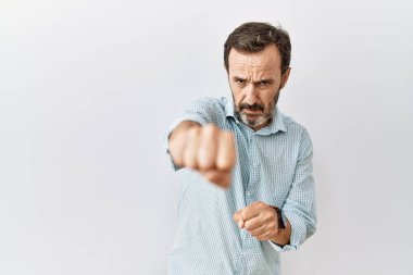 Orta yaşlı, sakallı İspanyol bir adam tecrit edilmiş arka planda duruyor. Yumruklarını yumrukluyor, saldırıyor, saldırıyor, tehdit ediyor ve şiddet uyguluyor. 