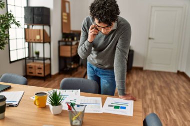 Genç İspanyol işadamı ofiste çalışan akıllı telefondan konuşuyor..